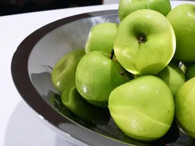 a bowl of green apples sitting on a table at Ixora Hotel Penang in Perai