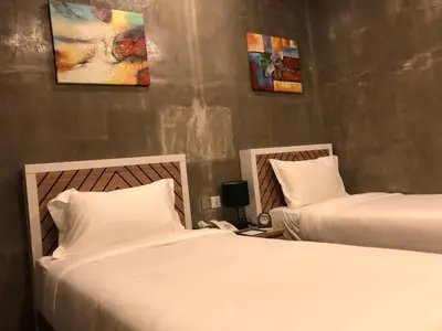two beds in a hotel room with white sheets at K Boutique Hotel in Teluk Intan
