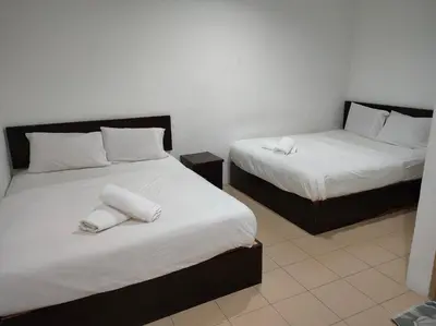 a bedroom with two beds with white sheets and towels at Hotel Star Inn in Teluk Intan