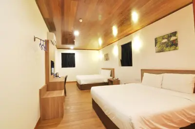a hotel room with two beds and a desk at Greencity Hotel in Sungai Petani