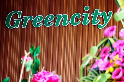 a sign that says greenity on a wooden wall with flowers at Greencity Hotel in Sungai Petani