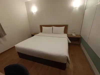 a bedroom with a white bed and a chair at Greencity Hotel in Sungai Petani