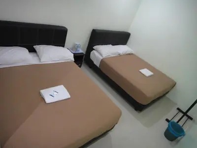 two beds in a hotel room with a laptop on them at Mines Inn Hotel in Gua Musang