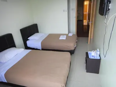 a hotel room with two beds and a television at Mines Inn Hotel in Gua Musang