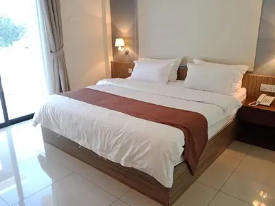 a bedroom with a large bed with white sheets at Oscar Suites Hotel in Sitiawan