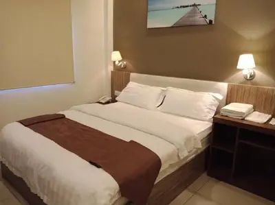 a hotel room with a bed and a telephone at Oscar Suites Hotel in Sitiawan