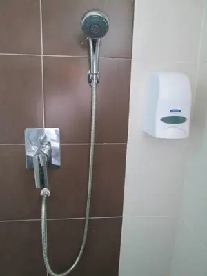 a shower with a hose attached to a wall at Oscar Suites Hotel in Sitiawan