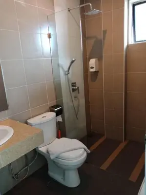 a bathroom with a shower with a toilet and a sink at Oscar Suites Hotel in Sitiawan