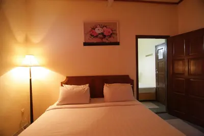 a bedroom with a bed and a lamp and a door at Anggerik Lodging in George Town