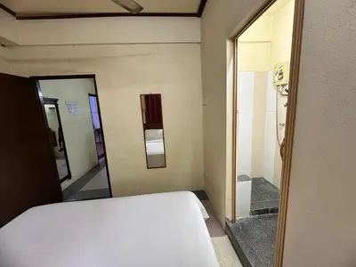 a bedroom with a white bed and a mirror at Anggerik Lodging in George Town