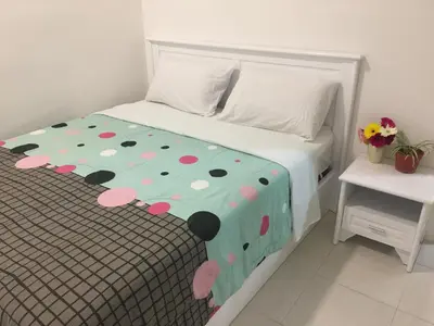 a white bed with a polka dot bedspread at Cameron Prima Apartment @ Cameron Jaya in Cameron Highlands