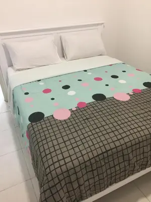 a bed with a polka dot blanket on it at Cameron Prima Apartment @ Cameron Jaya in Cameron Highlands