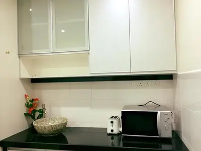 a kitchen with white cabinets and a counter with a microwave at Bukit Banyan Homestay Sungai Petani in Sungai Petani