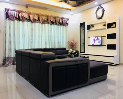 a living room with a black couch and a tv at Bukit Banyan Homestay Sungai Petani in Sungai Petani