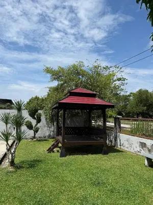 a gazebo with a red roof in the grass at Taiping Homestay Husna Afina in Taiping
