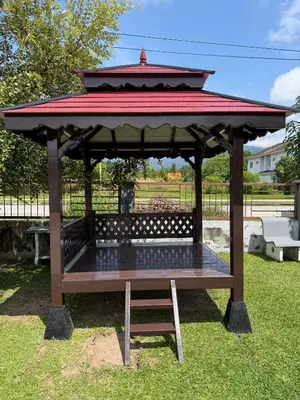 a wooden gazebo with a red roof on the grass at Taiping Homestay Husna Afina in Taiping