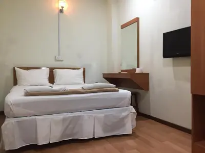 a bedroom with a bed with white sheets and a television at Hotel Sri Malim in Tanjung Malim