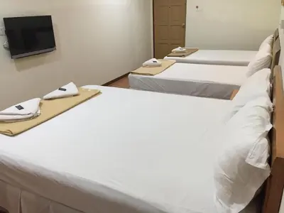 a room with three beds and a flat screen tv at Hotel Sri Malim in Tanjung Malim