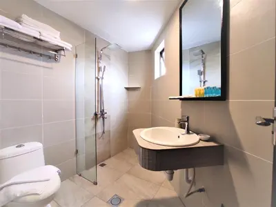 a bathroom with a sink and a toilet and a mirror at Apple Suites Hotel in Sitiawan