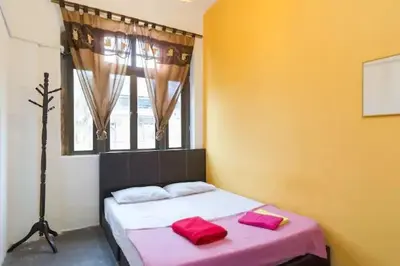 a bedroom with a bed with two red pillows on it at Cocoa Mews Cafe and Homestay in George Town