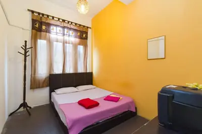 a small bedroom with a bed and a suitcase at Cocoa Mews Cafe and Homestay in George Town