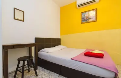 a bedroom with a bed with a stool and a desk at Cocoa Mews Cafe and Homestay in George Town