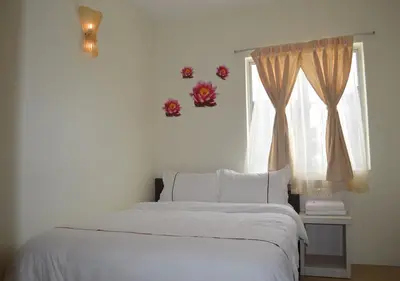 a bedroom with a white bed and a window at Angsoka Hotel in Teluk Intan
