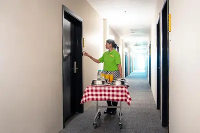 a woman standing in a hallway with a table with pots and pans at Flemington Hotel in Taiping
