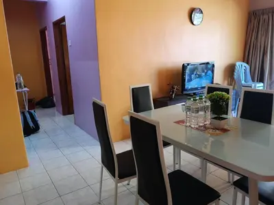 a dining room with a table with chairs and a television at Kelly Cozy cottage in Kampar