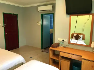 a bedroom with a bed and a desk and a mirror at Kangsar Hotel in Kuala Kangsar