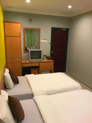 a room with two beds and a tv on a desk at Kangsar Hotel in Kuala Kangsar