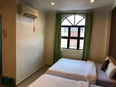 a bedroom with two beds and a window at Kangsar Hotel in Kuala Kangsar