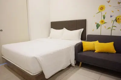 a bedroom with a bed and a couch with yellow pillows at PM Octagon Ipoh Suites & Apartment 2 in Ipoh