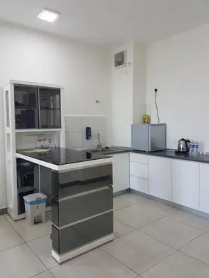 a kitchen with white cabinets and black counter tops at PM Octagon Ipoh Suites & Apartment 2 in Ipoh