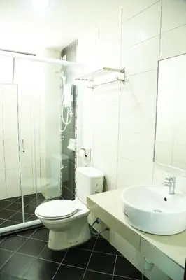a white bathroom with a toilet and a sink at Marina Heights Resort in Lumut
