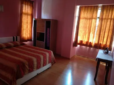 a bedroom with a bed and two windows and a wooden floor at Tenggafriz holidays in Cameron Highlands