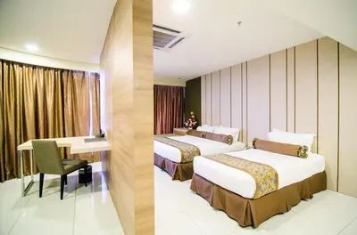 a hotel room with two beds and a desk at Hotel Sfera in Lumut