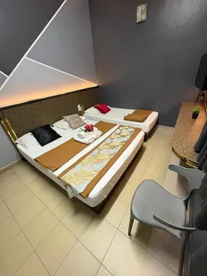 two beds in a room with a chair at Weng Kong Hotel in Slim River