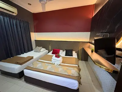 a room with two beds and a flat screen tv at Weng Kong Hotel in Slim River