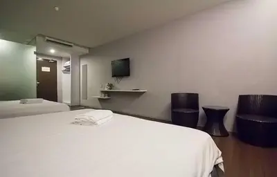 a bedroom with a white bed and two chairs at Chariton Hotel Ipoh in Ipoh