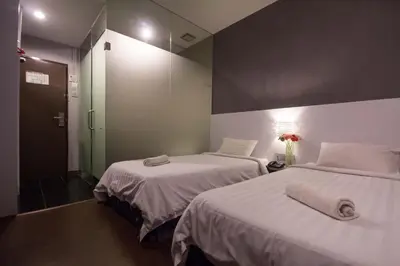 two beds in a hotel room with a mirror at Chariton Hotel Ipoh in Ipoh