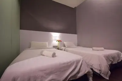 two beds in a room with white sheets at Chariton Hotel Ipoh in Ipoh