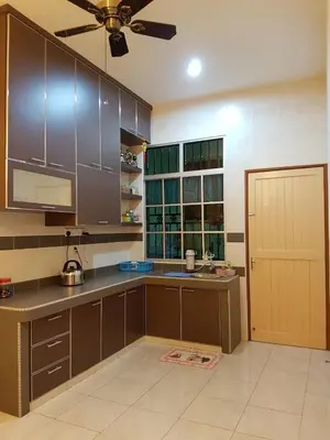 a kitchen with brown cabinets and a ceiling fan at Big Garden Homestay in Pantai Remis