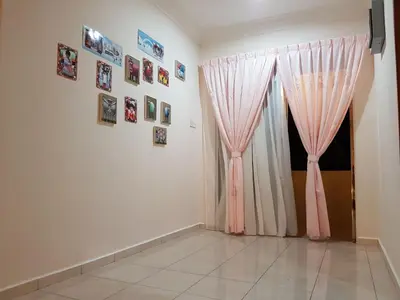 a room with pink curtains and pictures on a wall at Big Garden Homestay in Pantai Remis