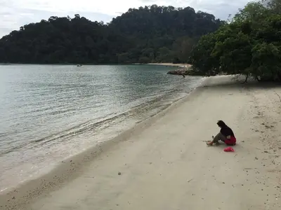 a man sitting on a beach next to the water at Pangkor Damai in Pangkor