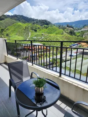 a table and chairs on a balcony with a view at Peony Square Residences in Cameron Highlands