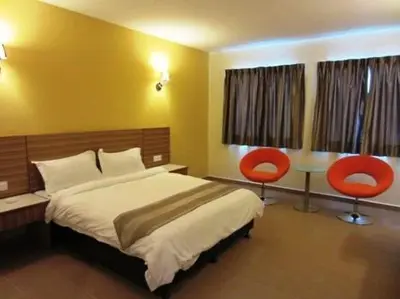 a bedroom with a bed and two red chairs at Grand Court Hotel in Teluk Intan
