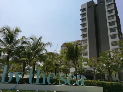 a sign in front of a building with palm trees at By The Sea BeachFront Penang in Batu Ferringhi