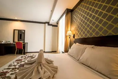 a bedroom with a bed and a desk and a mirror at De' Garden Hotel, Butterworth in Butterworth
