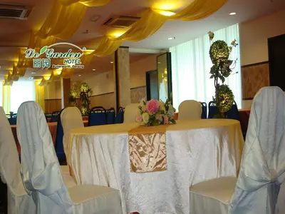 a table with white chairs and a table with flowers on it at De' Garden Hotel, Butterworth in Butterworth